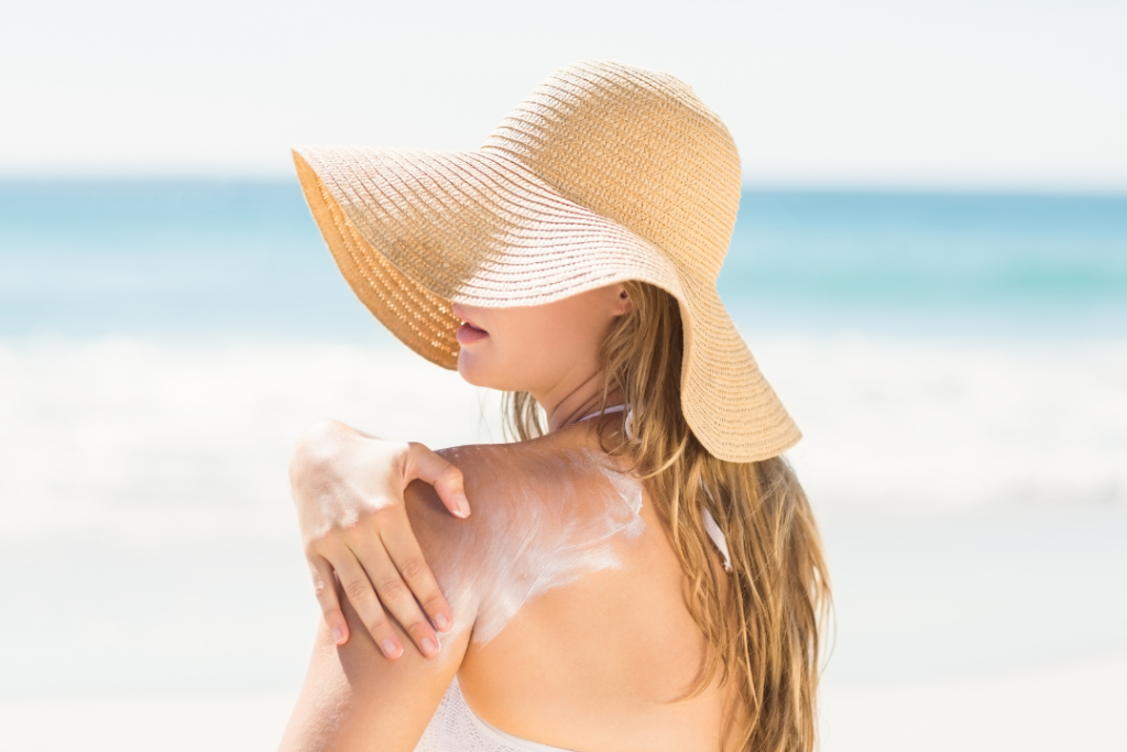Woman applying sun burn lotion at beach while taking sun bath.