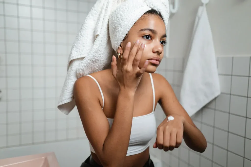 A girl applying cream on her face.